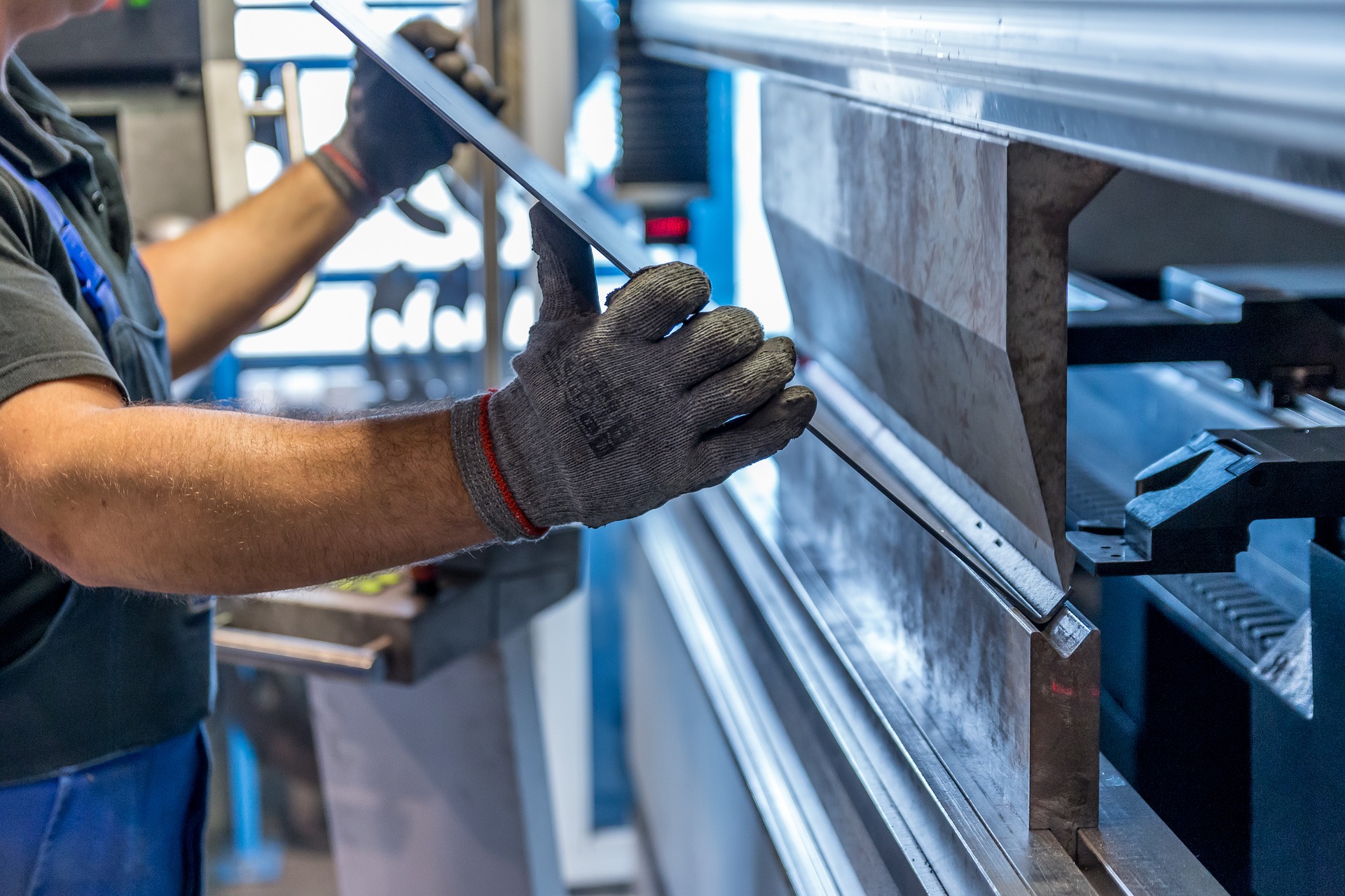 Worker bending a sheet of stainless steel on a break machine.